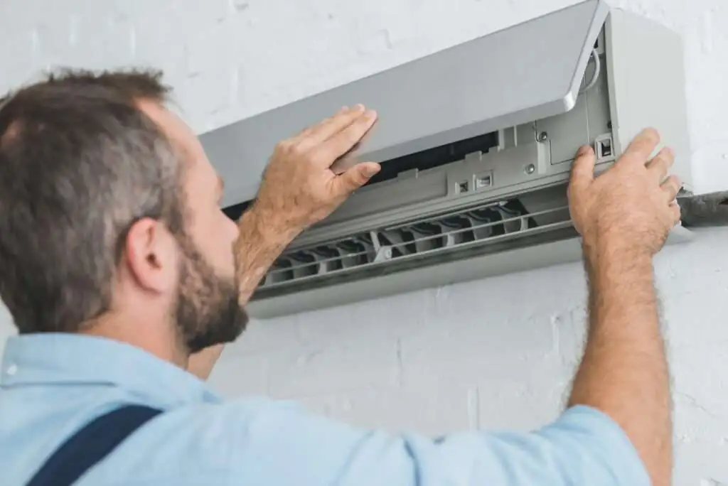 Monteur voert onderhoud uit aan een airco-unit aan de muur – Grijzeboom.com