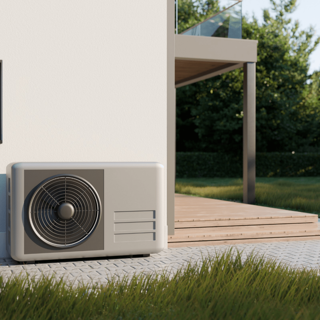 Buitenunit van een warmtepomp naast een woning met een groene tuin en terras