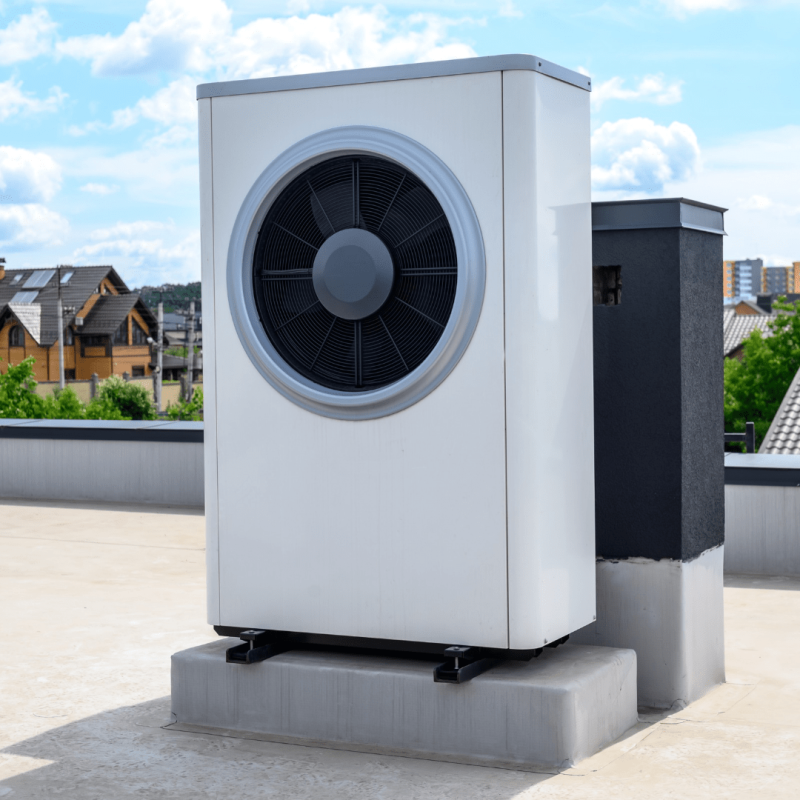 Grote buitenunit van een warmtepomp op een betonnen fundatie op een plat dak