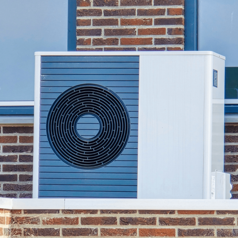 Close-up van een warmtepompbuitenunit voor een bakstenen gevel